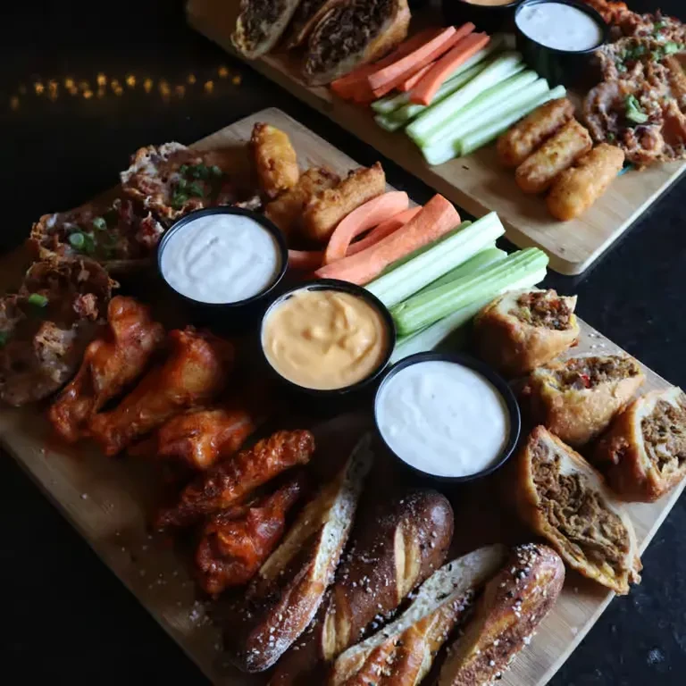 Two wooden boards with various fried appetizers, pretzels, and vegetables.