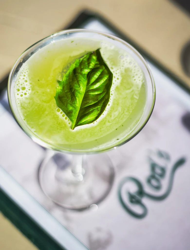Green cocktail in martini glass with leaf garnish; 'Rod's' logo.