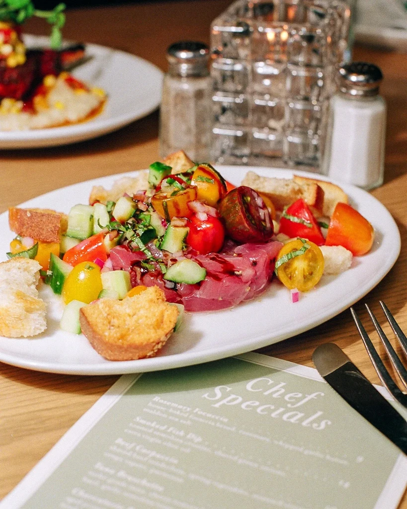 Thinly sliced tuna topped with colorful diced vegetables and toasted bread.