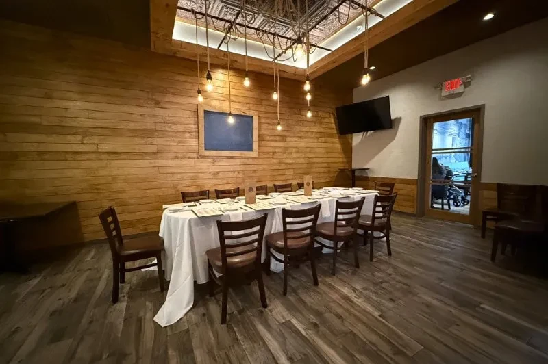 Rustic private dining room with long table and industrial lighting.