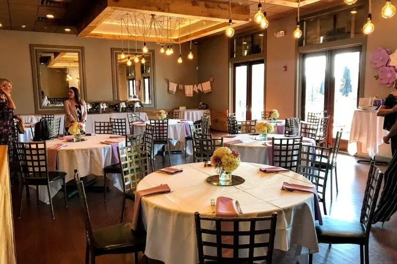 Restaurant event space with purple table decor, flowers, and a buffet.