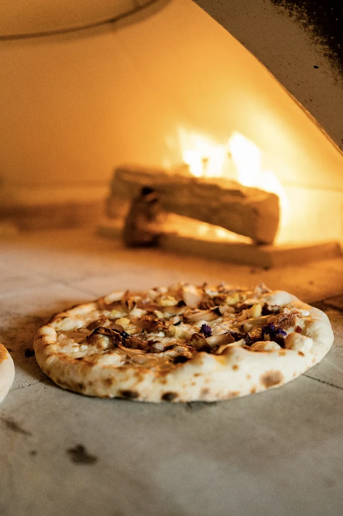 Pizza with blistered crust and toppings in a glowing wood-fired oven.