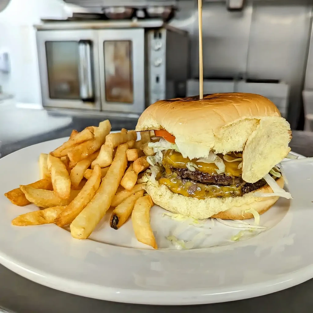 Double cheeseburger, french fries, and chip on a white plate.