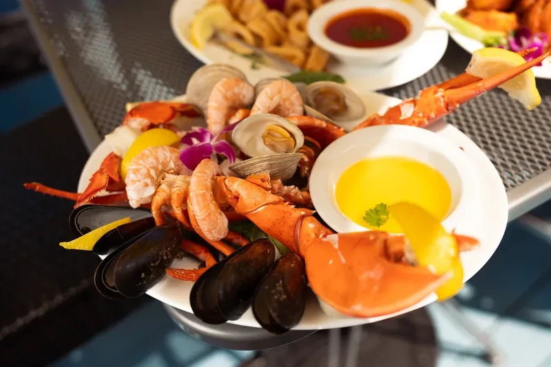 Restaurant seafood platter with lobster, shrimp, mussels, clams, and sauces.