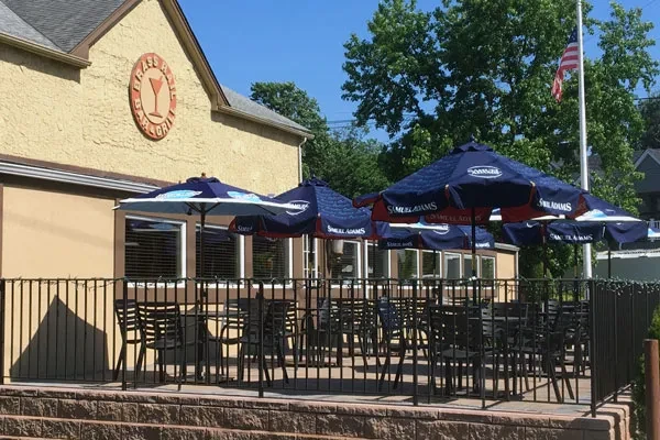Exterior of Brass Rail Grill restaurant with patio and Samuel Adams umbrellas.