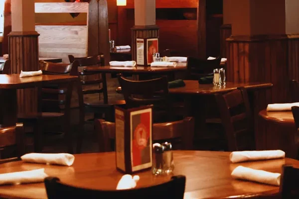 Empty, warm restaurant interior with dark wooden tables and chairs.