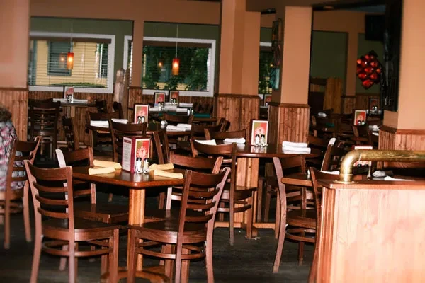 Rustic restaurant interior with dark wooden tables, two-tone walls, pendant lights.