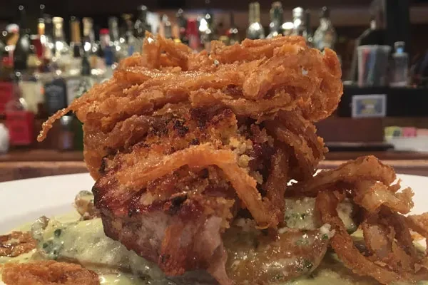 Crispy golden-brown fried onions atop a main dish with green sauce.