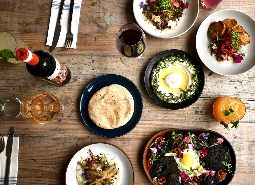 Rustic table laden with diverse, beautifully presented food dishes and various drinks.