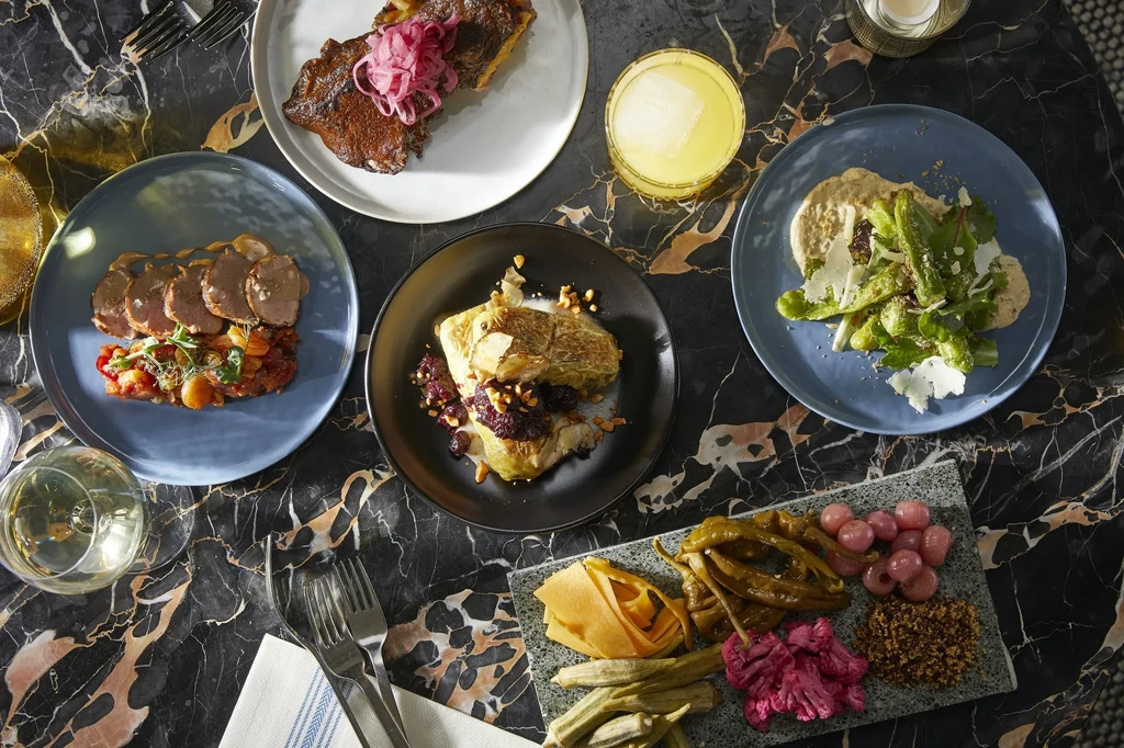 Overhead view of a diverse meal spread on a dark, veined marble table.