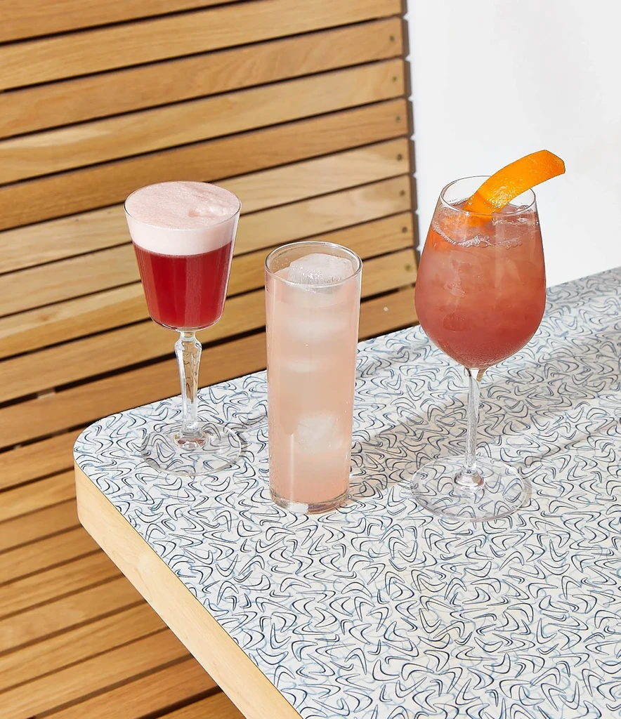 Three vibrant drinks on a unique patterned tabletop.