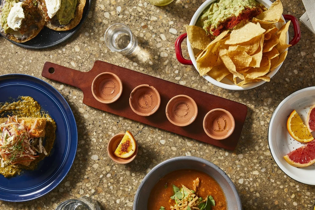 Top-down view of vibrant Mexican dishes and drinks on a speckled counter.
