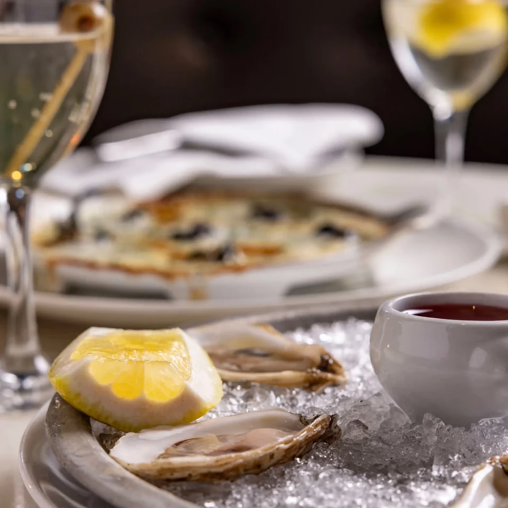 Close-up of fresh oysters on ice with lemon and red sauce.