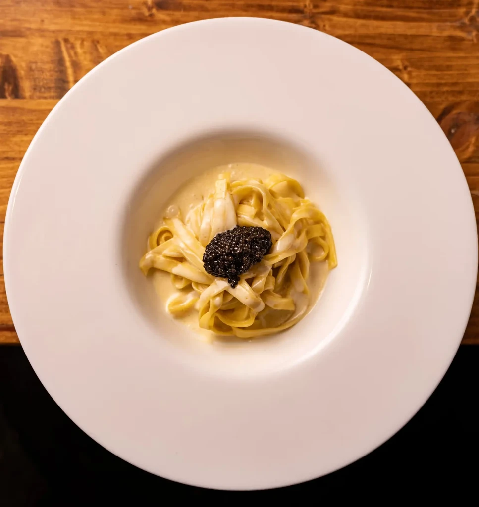 Creamy pasta dish with a mound of shimmering black caviar.