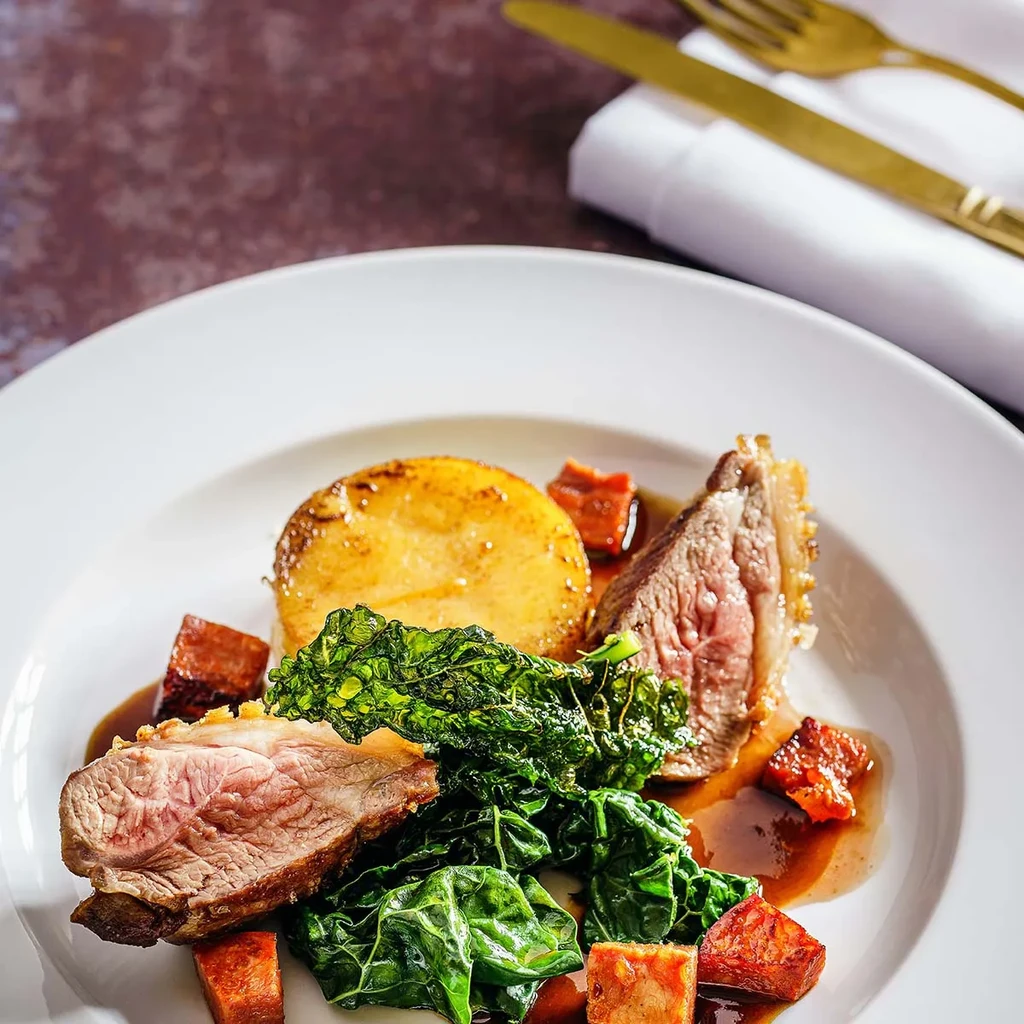 Plated roasted meat, potato, green vegetables, and brown sauce.