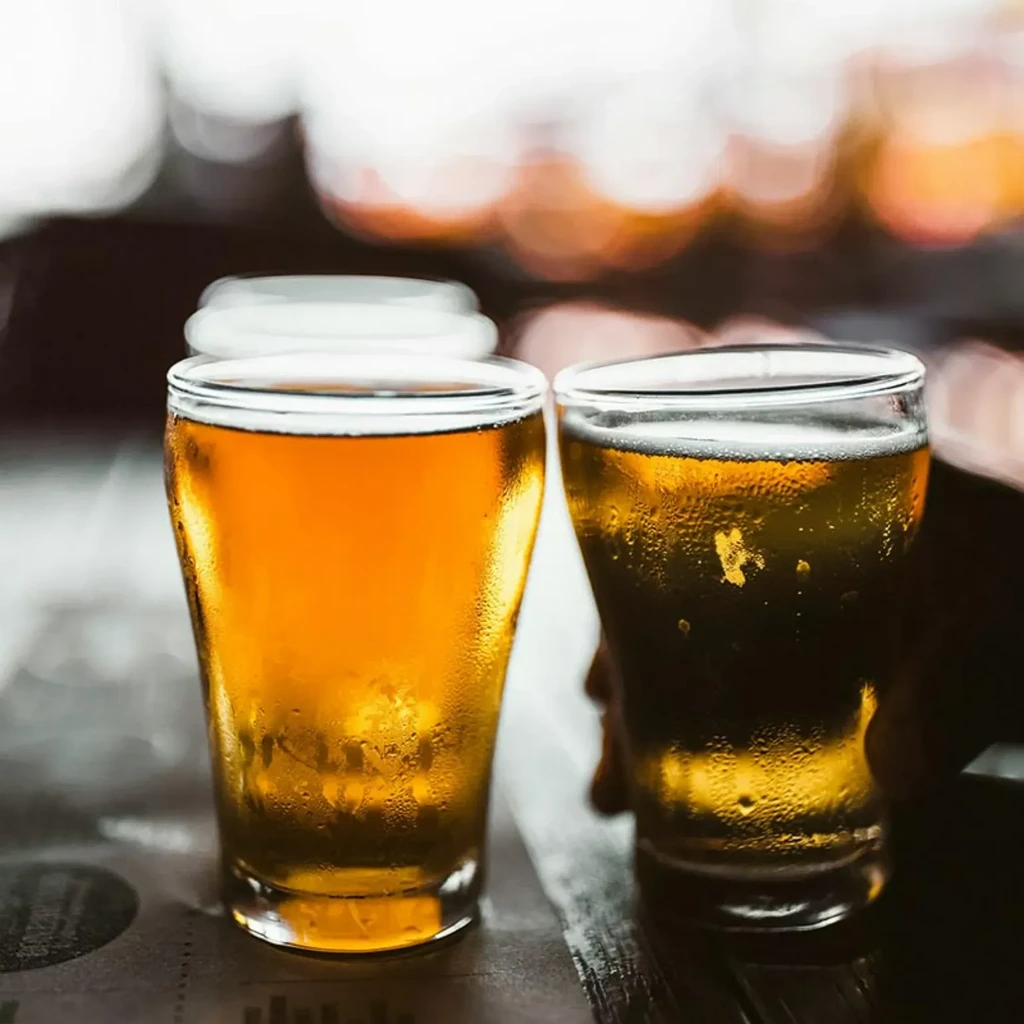 Light and dark amber beers in cold glasses on a bar.