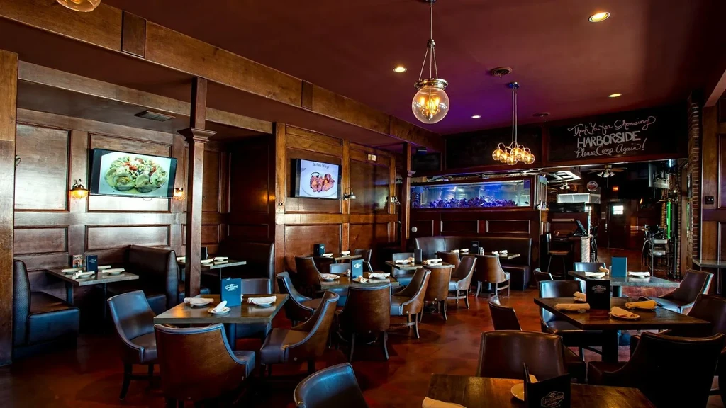 Dark wood restaurant interior with red ceiling, tables, and illuminated aquarium.