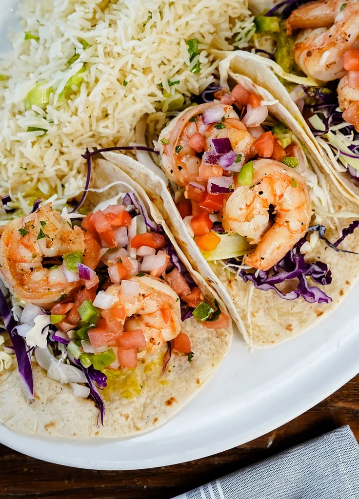Three shrimp tacos with pico de gallo and herbed rice.