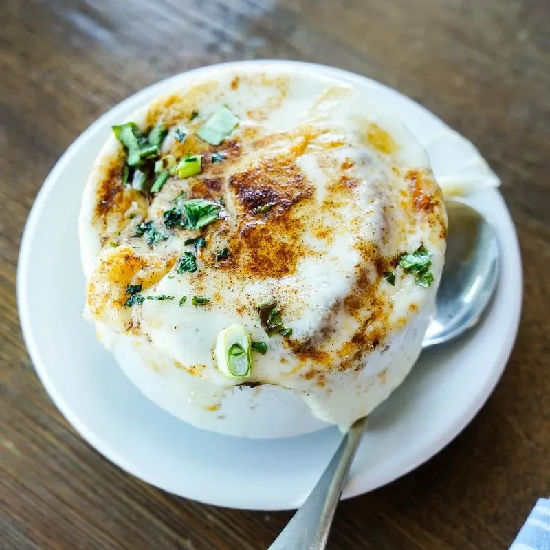 Baked dish topped with browned melted cheese and green herbs.
