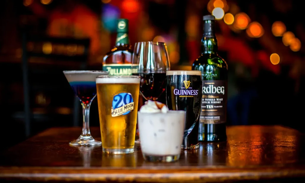 Assorted alcoholic drinks including beer, whiskey, wine, and cocktails on a bar.