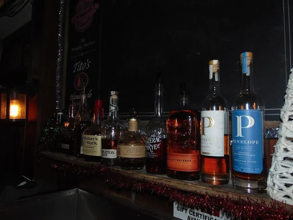 Bottles of bourbon and whiskey on a shelf at a bar.