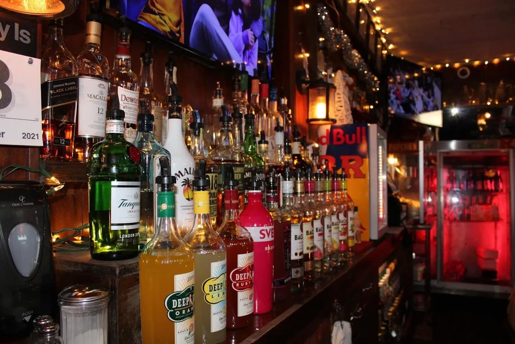 A well-stocked bar with various liquor bottles and string lights.