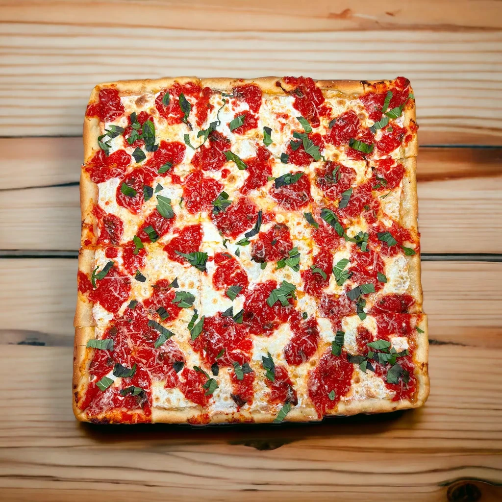 Top-down view of a rectangular pizza with red sauce, cheese, and basil.