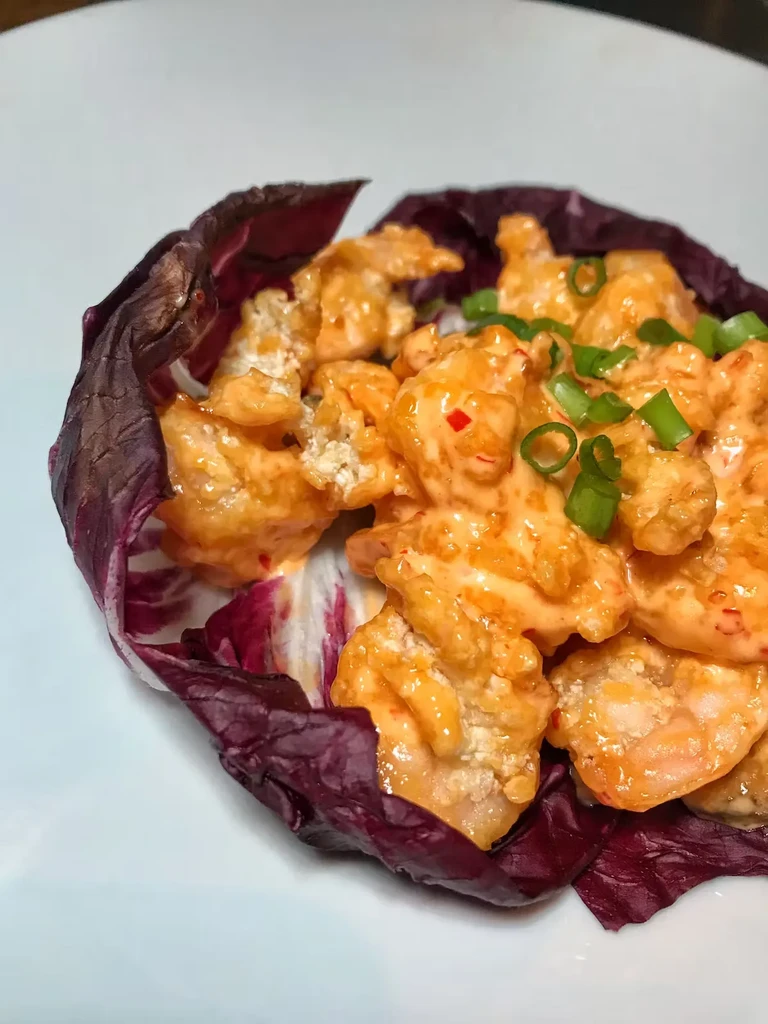 Bang Bang Shrimp with red lettuce, topped with green onions.