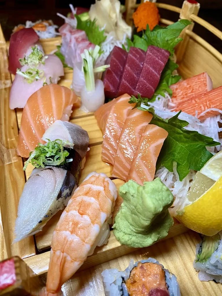 A close-up of various sushi and sashimi arranged on a wooden platter.