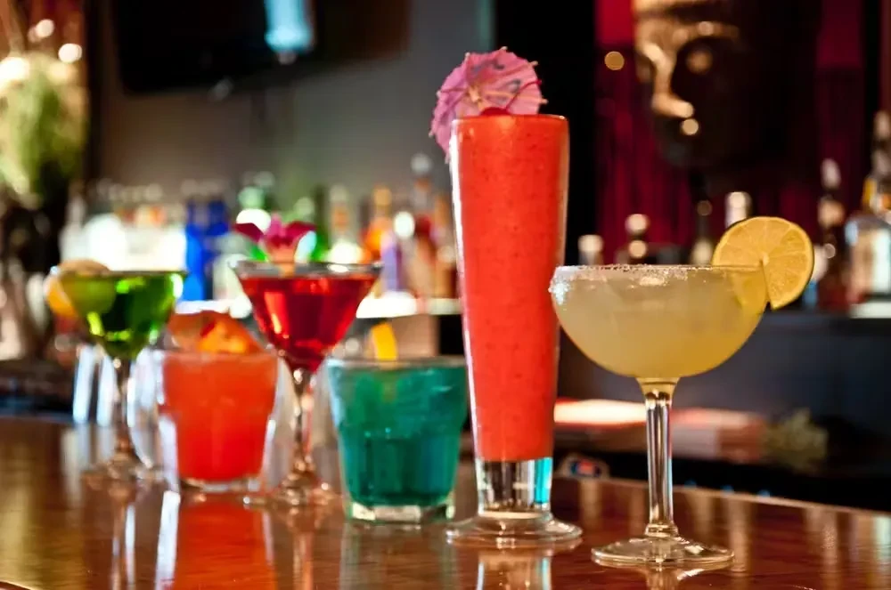 A row of colorful cocktails on a bar counter.