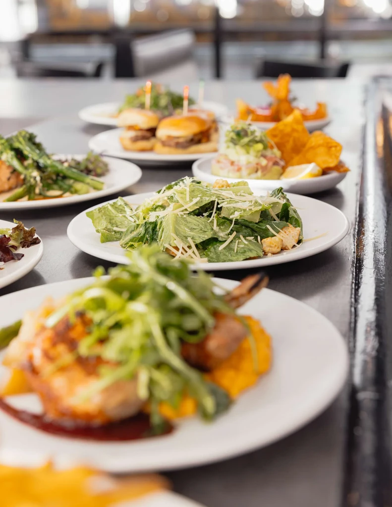 Various restaurant dishes: chicken, Caesar salad, mini burgers, and fried shrimp.
