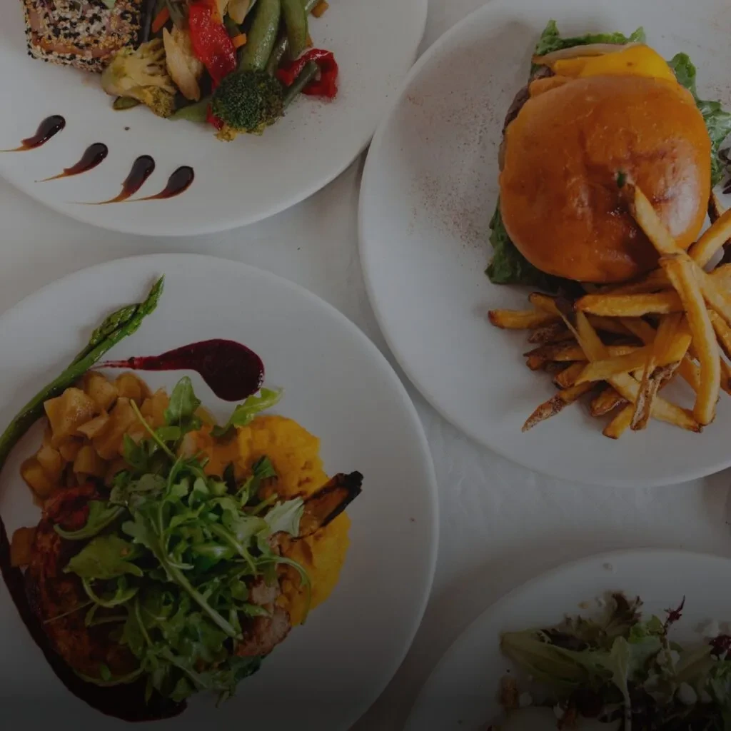 Overhead view of several diverse, artfully plated restaurant meals.