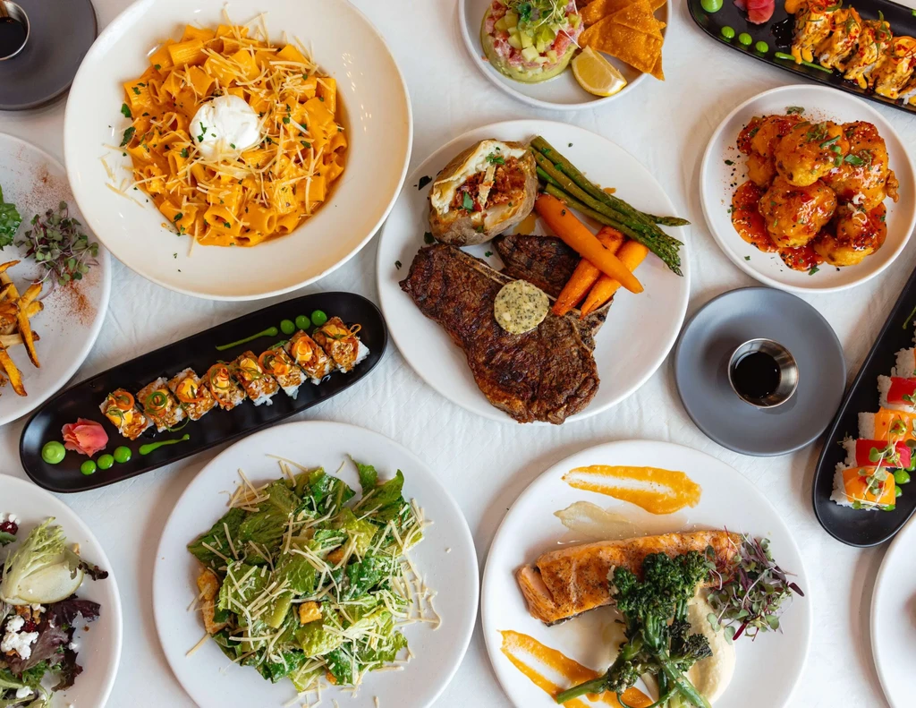 Overhead view of a table with diverse, beautifully plated restaurant food.