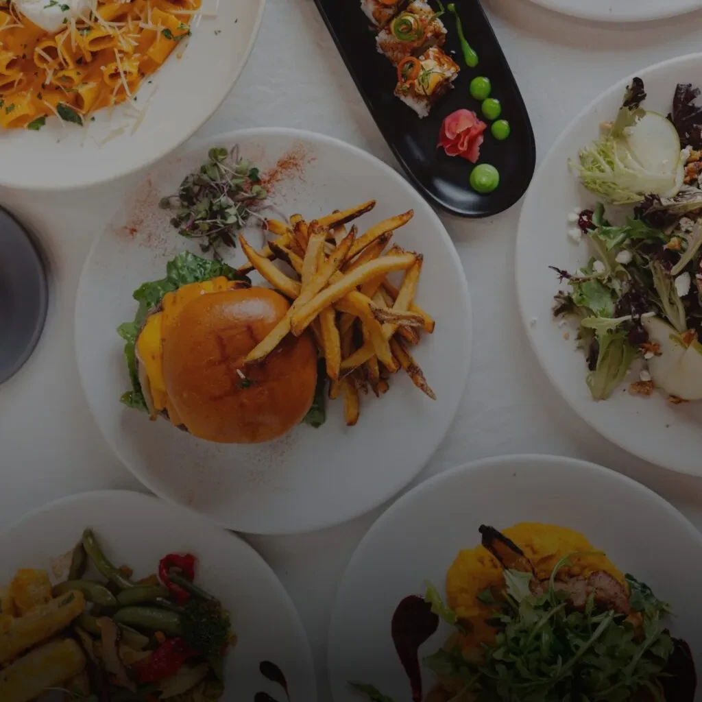 Top-down view of diverse restaurant dishes, including a prominent burger and fries.