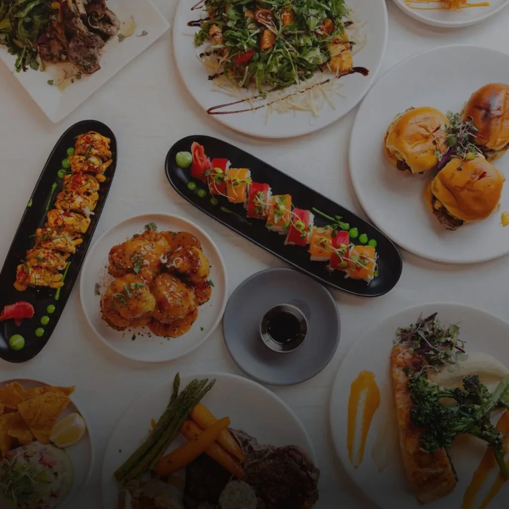 Overhead view of a white table laden with diverse restaurant dishes.