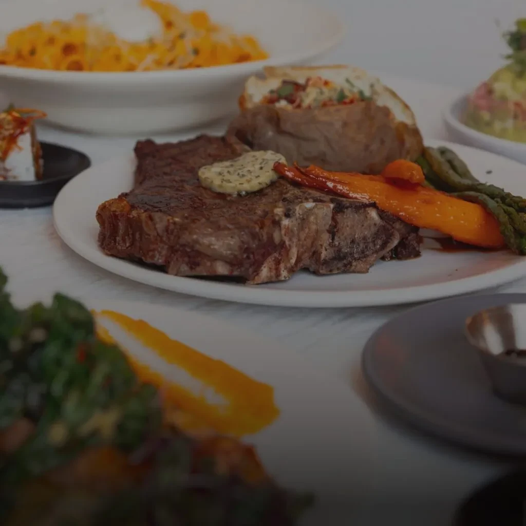 T-bone steak, herb butter, roasted vegetables, baked potato, macaroni and cheese.