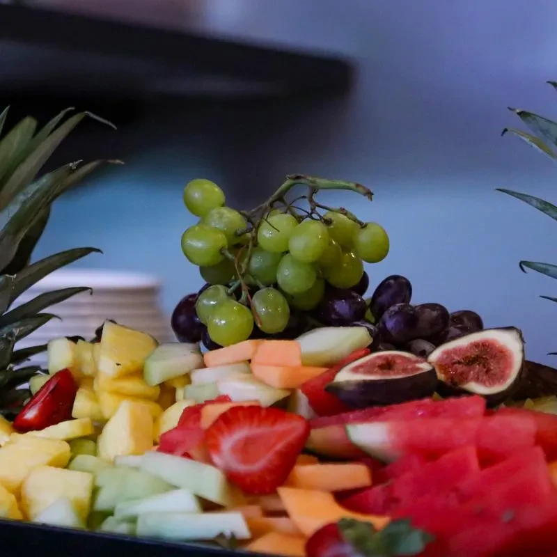 Colorful, well-arranged platter of cut fruit: grapes, melon, strawberries, figs.