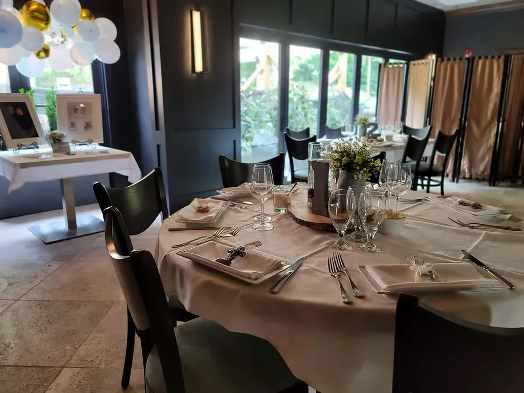 Dining room with set tables, floral centerpieces, balloons, and personal photos.