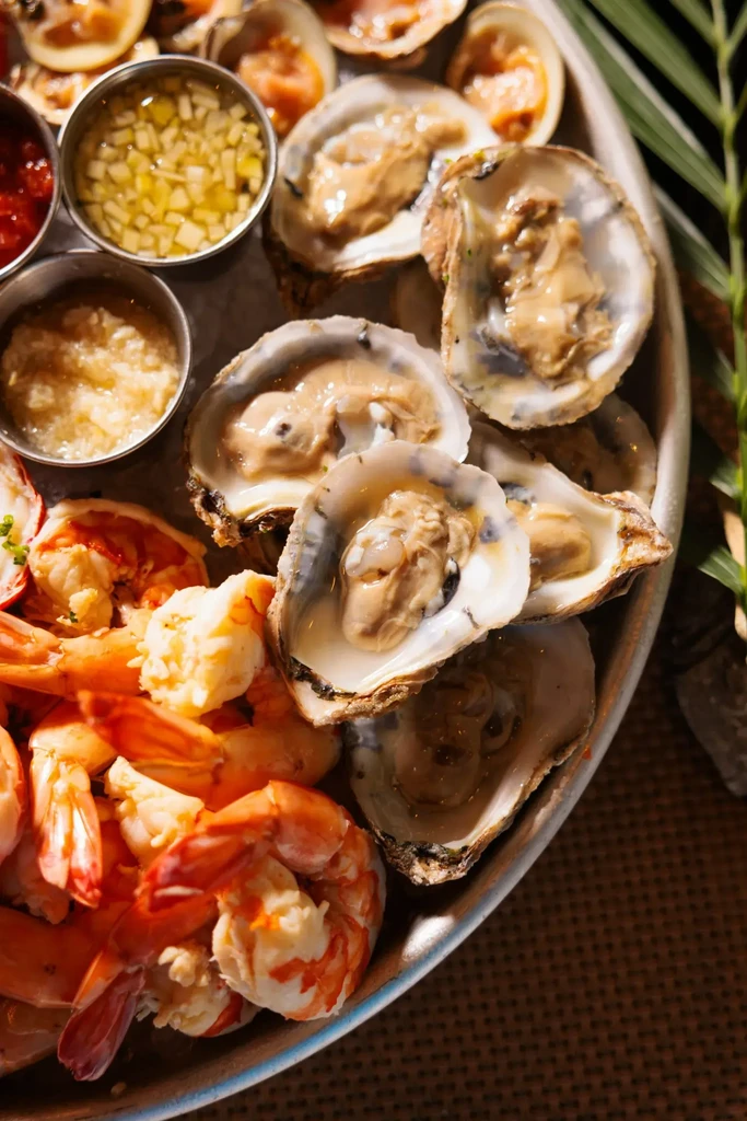 Top-down seafood platter with fresh oysters, peeled shrimp, and sauces.