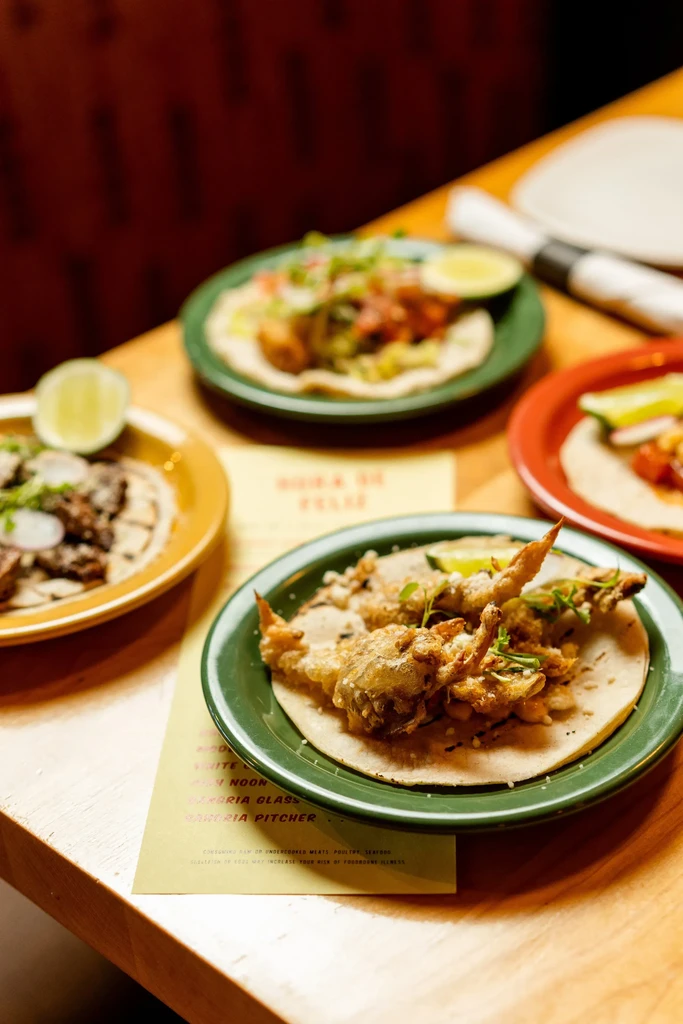 Overhead view of four taco plates, including crab and carne asada tacos.
