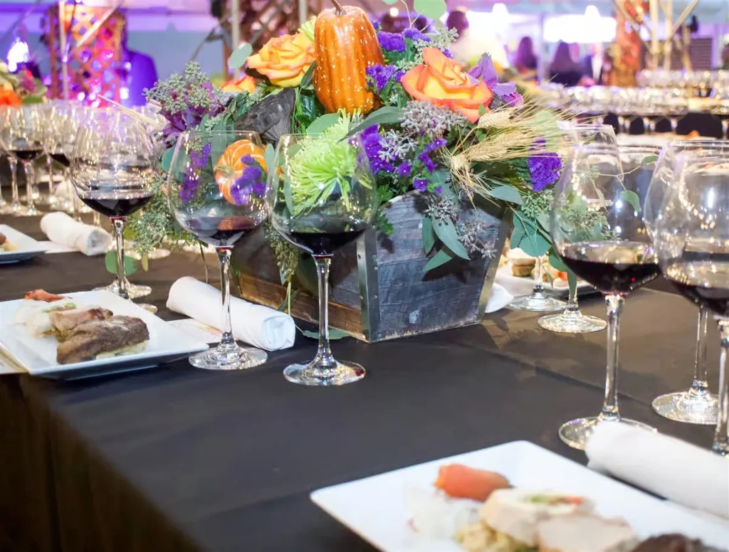 Dining table with red wine, appetizers, and autumnal centerpiece.