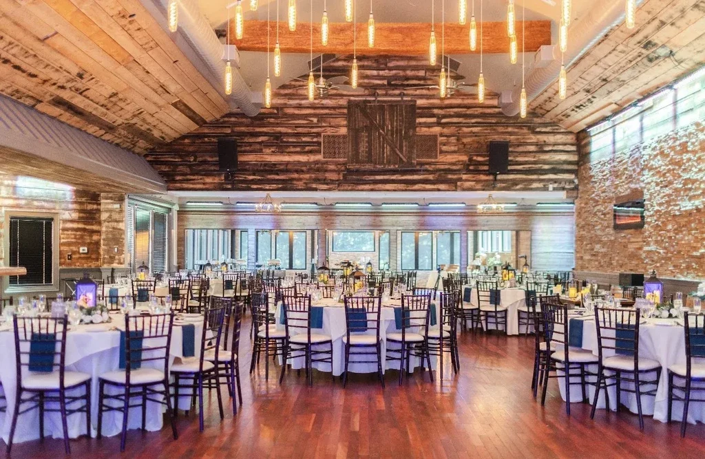 Spacious rustic dining hall with vaulted wood ceiling and set tables.
