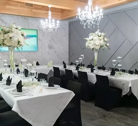 Elegantly set event space with white floral decor and crystal chandeliers.