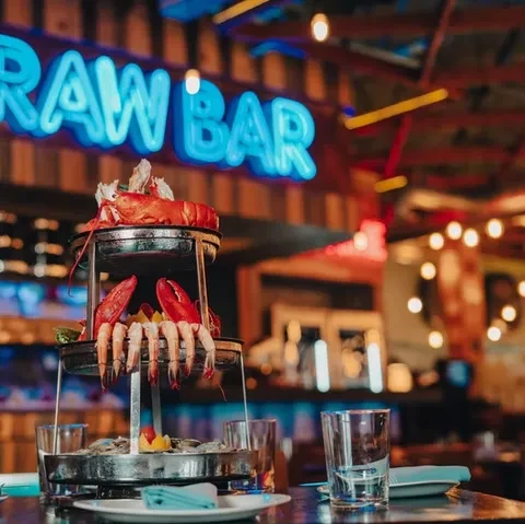 Seafood tower with lobster, shrimp, and oysters at a raw bar.