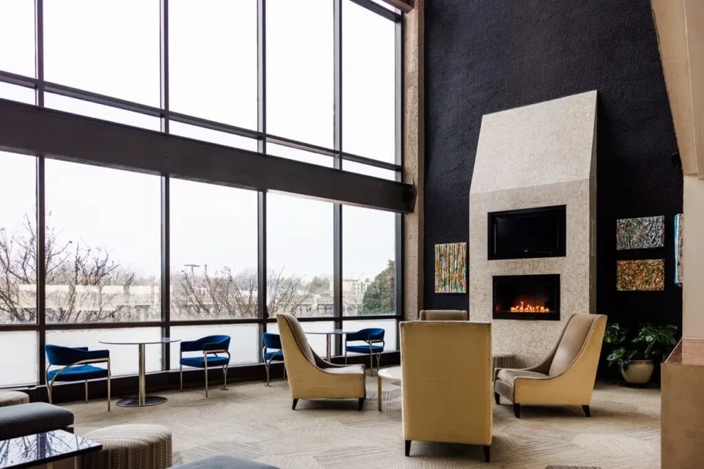 Spacious modern lounge with large windows, fireplace, and comfortable seating.
