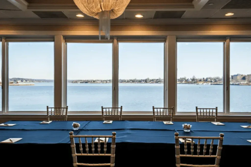 Conference room with blue table, gold chairs, and scenic water view.