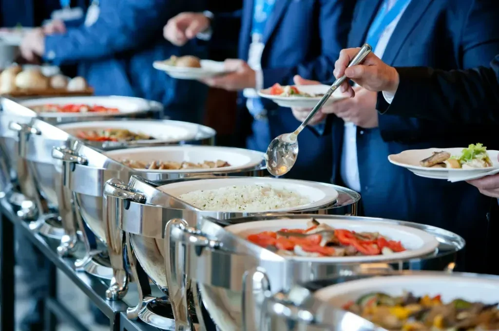 People in formal attire serve themselves from a hot food buffet.