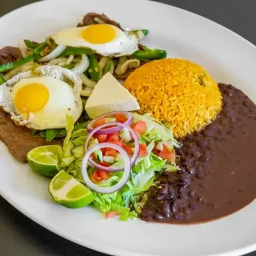 Large plate with steak, sunny eggs, rice, beans, salad, and cheese.