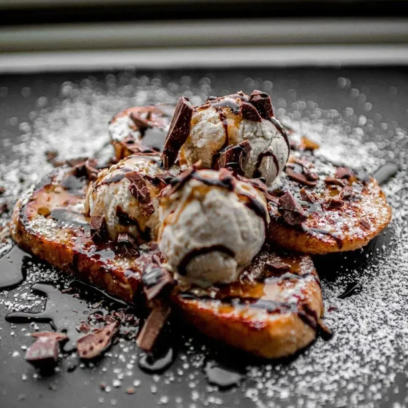 Golden French toast with ice cream, chocolate sauce, and powdered sugar.