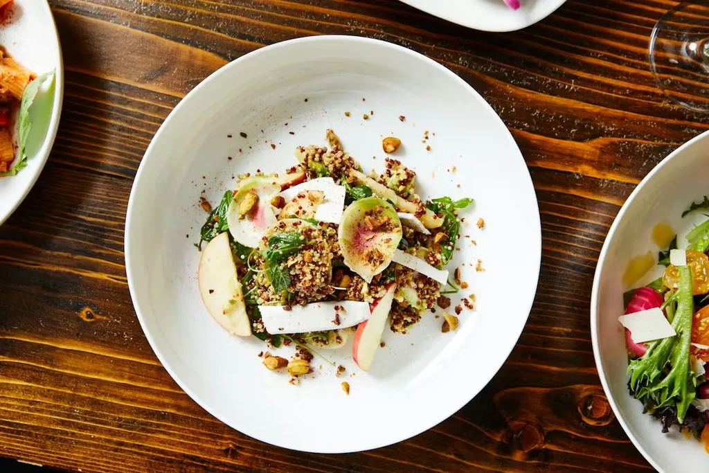 Vibrant quinoa and apple salad with cheese and radish on wood.